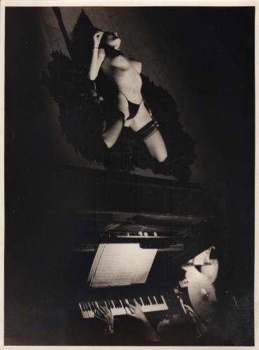 Hombre al piano, mujer semidesnuda sobre escenario