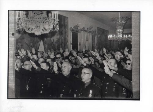 Grupo de militares y altos cargos de la Iglesia cantando y haciendo el saludo fascista