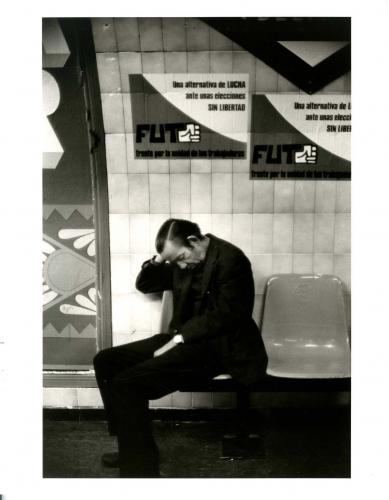 Hombre dormido en el metro, con carteles del FUT al fondo